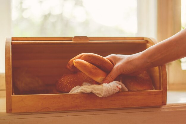 Mulher tirando pão de uma caixa de pão na cozinha de casa