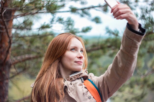 Foto mulher tirando selfie enquanto está de pé contra árvores