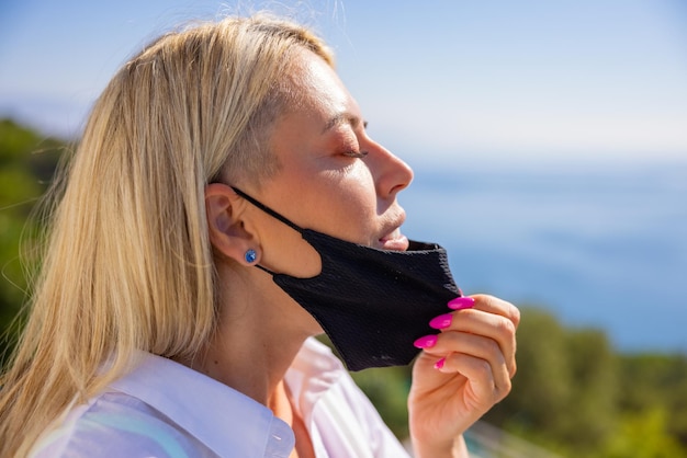 Mulher tirando sua máscara facial e respirando ar fresco ao ar livre