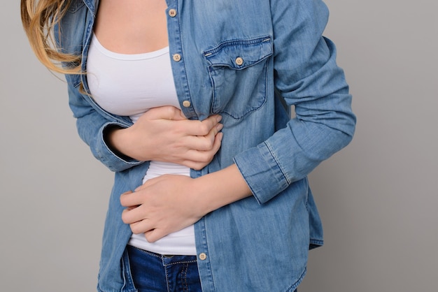 Mulher tocando a barriga em fundo cinza isolado