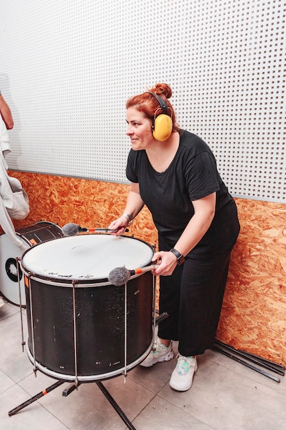 Mulher tocando bateria com protetores auriculares