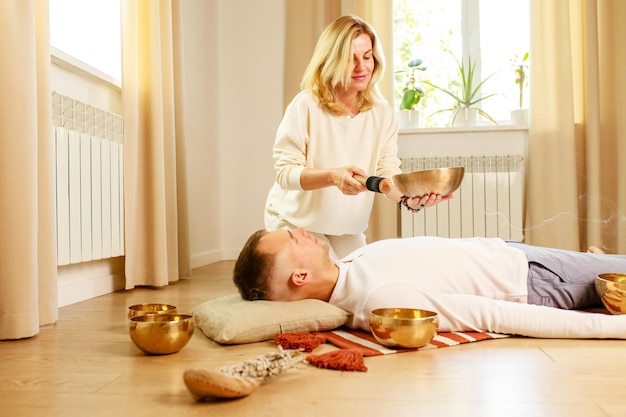 Mulher tocando em uma tigela de canto tibetano maling massagem meditação para um homem