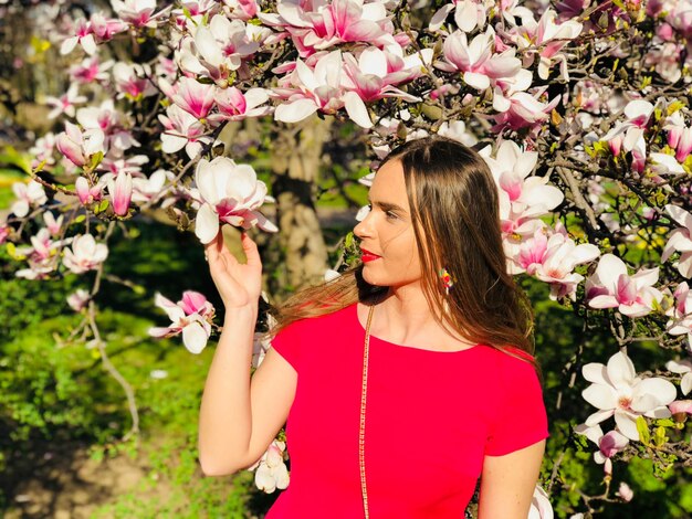 Foto mulher tocando flores que florescem na árvore