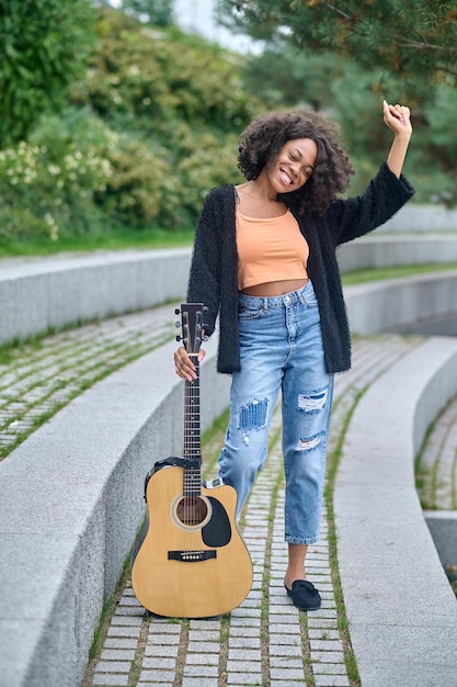 Mulher tocando guitarra em pé no parque durante o dia