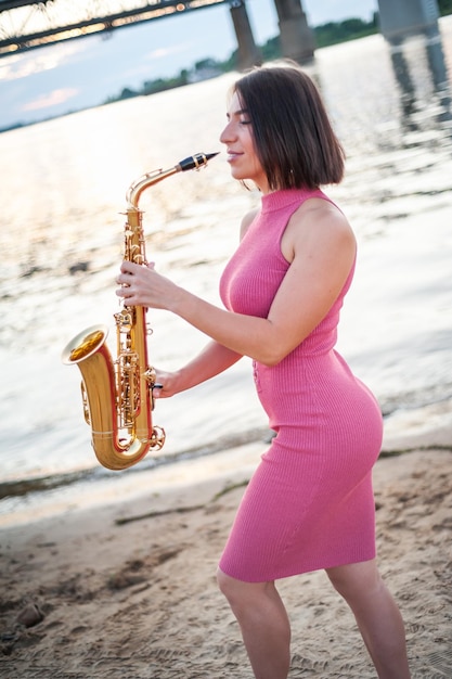 Mulher tocando saxofone ao pôr do sol
