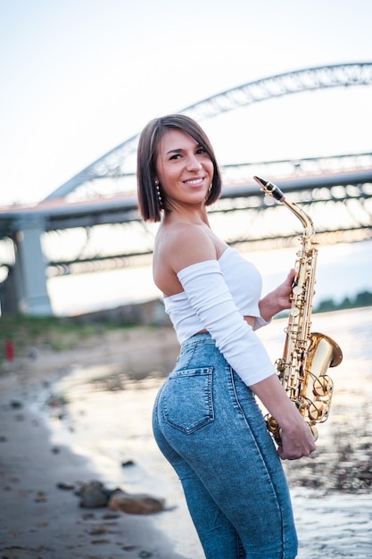 Mulher tocando saxofone ao pôr do sol