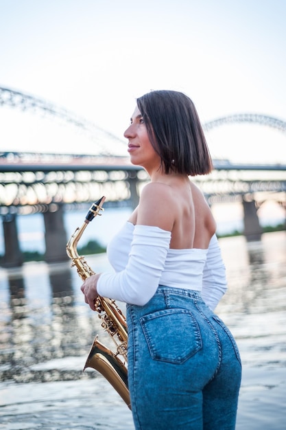 Mulher tocando saxofone ao pôr do sol