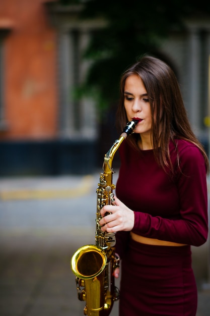 Mulher tocando saxofone nas ruas da cidade