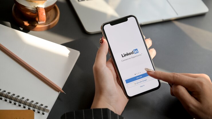 Foto mulher tocando smartphone com aplicativo linkedin.