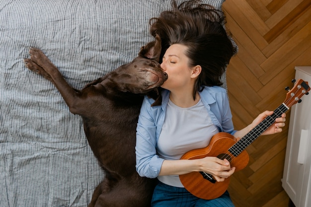 Mulher tocando violão ou ukulele com o cachorro