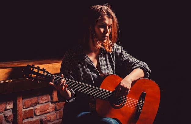 Fotos de Triste mulher jovem sentada com guitarra nas mãos