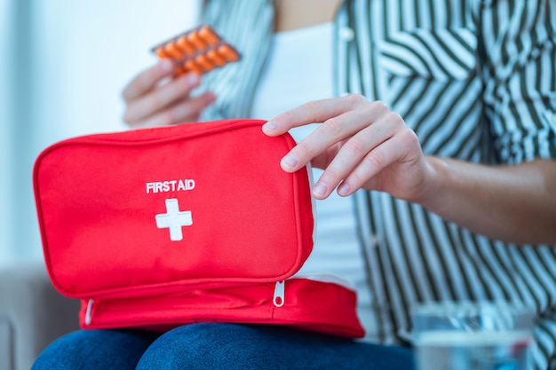 Foto mulher toma remédio de dor e doença em casa. kit médico de primeiros socorros