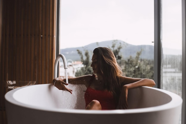 Mulher tomando banho e relaxando em uma banheira moderna