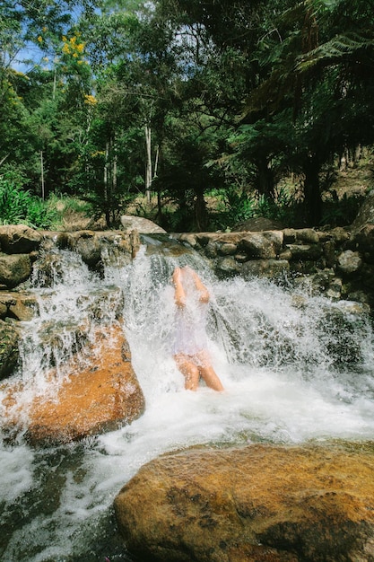 Foto mulher tomando banho em uma cachoeira na floresta