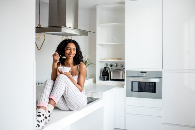 Mulher tomando café da manhã com telefone móvel