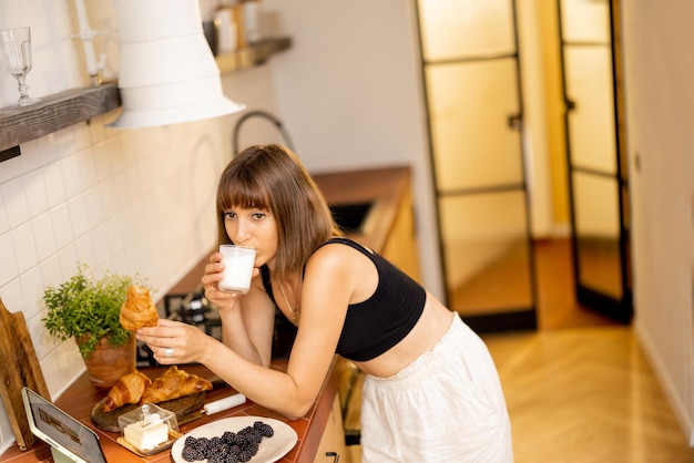 Mulher tomando café da manhã na cozinha em casa