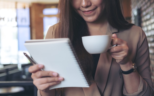 mulher tomando café e olhando para um notebook