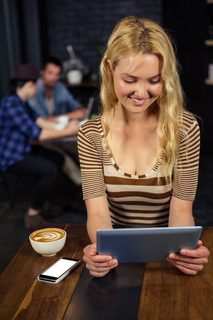 Mulher tomando café e usando tablet