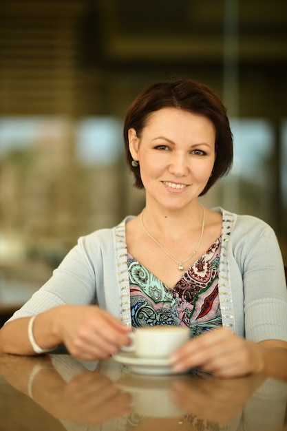 Mulher tomando café em uma xícara em um restaurante