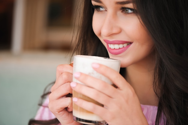 Mulher tomando café quente cappuccino e comendo bolo em um café.