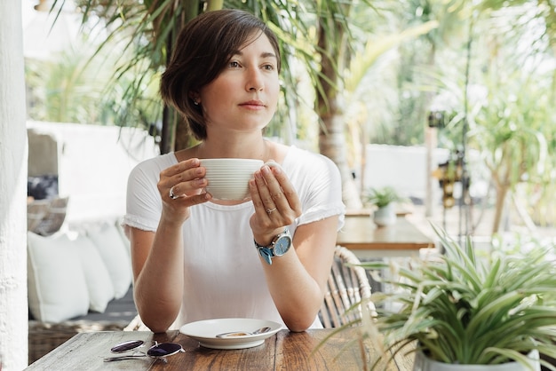 mulher tomando cappuccino em um café ao ar livre