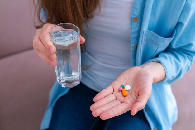 Mulher tomando pílulas e vitaminas para o bem-estar. Cuidados de saúde e tratamento de doenças.