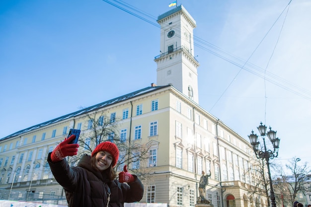 Mulher tomando selfie em seu telefone prefeitura de lviv no fundo