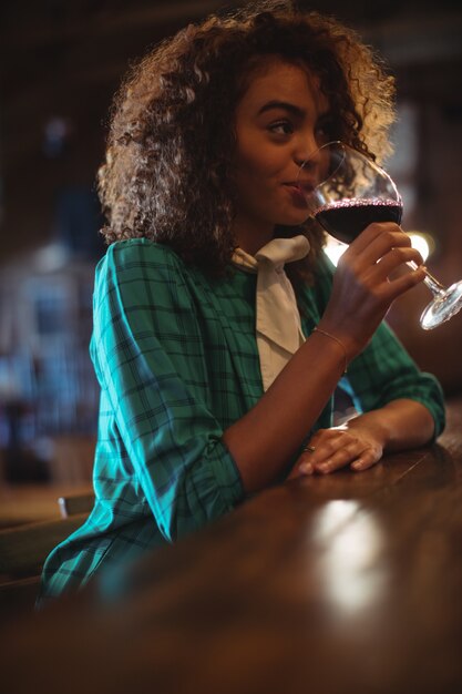 Mulher tomando vinho no balcão do bar