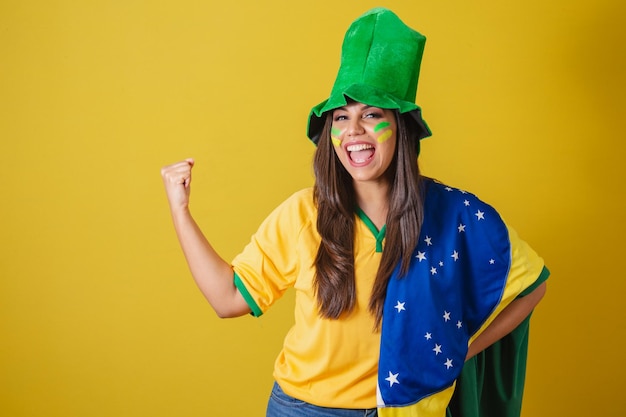 Mulher torcedora da Copa do Mundo Brasil 2022 vestindo roupa típica de fã para ir ao jogo bandeira brasileira e festa de chapéu verde