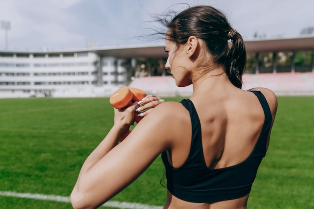 Mulher trabalha com barbells no estádio verde