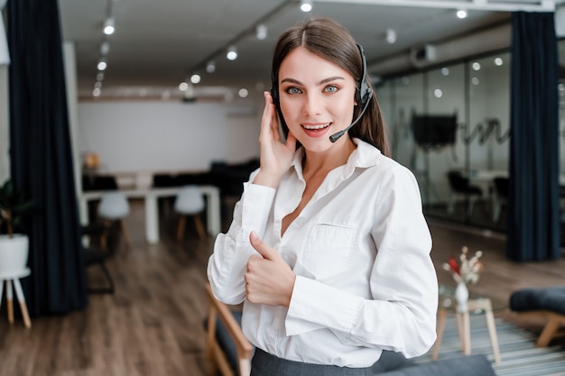 Foto mulher trabalha como operador de suporte de call center com fone de ouvido aparecendo polegares e sorrindo