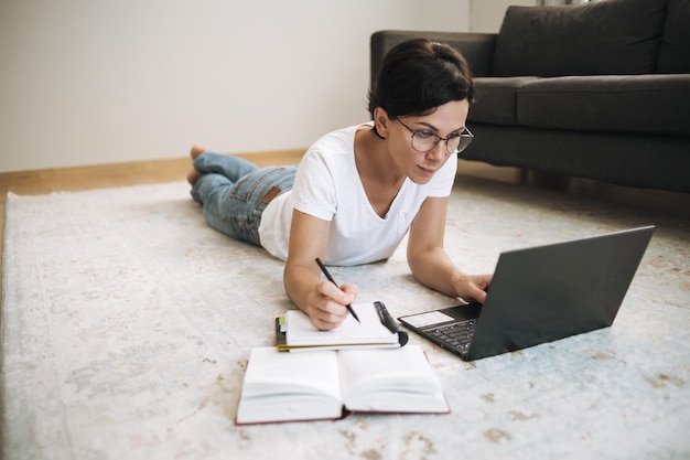 Foto mulher trabalha em um laptop em casa morena atraente de meia-idade com computador