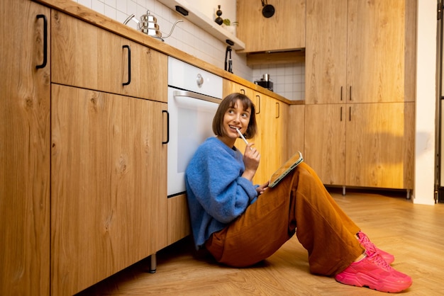 Mulher trabalha em um tablet digital enquanto está sentada no chão da cozinha