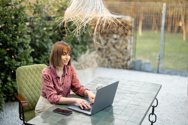 Mulher trabalha no laptop online no jardim ao ar livre
