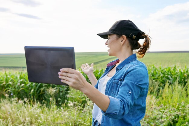 Mulher trabalhadora agrícola inspecionando chamada de vídeo de campo de milho usando tablet digital