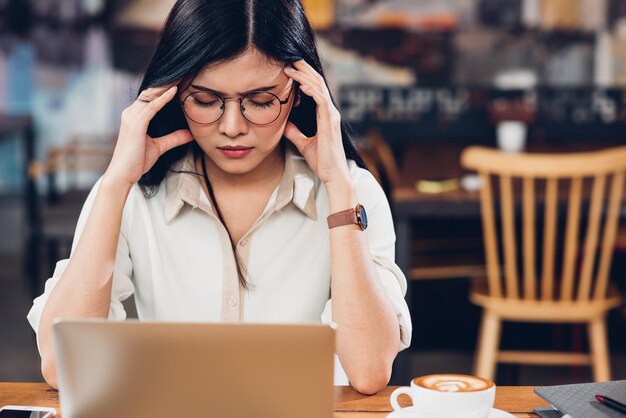 Mulher trabalhadora freelancer de estilo de vida e computador portátil, dor de cabeça infeliz no trabalho na cafeteria