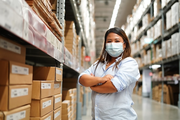 Mulher trabalhadora inspecionando estoque de produtos enquanto trabalhava em um grande armazém.