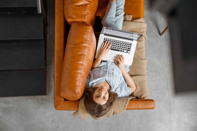 Mulher trabalhando com laptop em casa no sofá