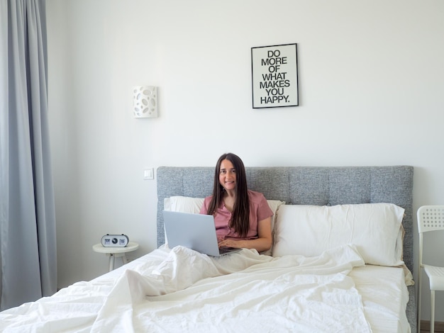 Mulher trabalhando com laptop na cama