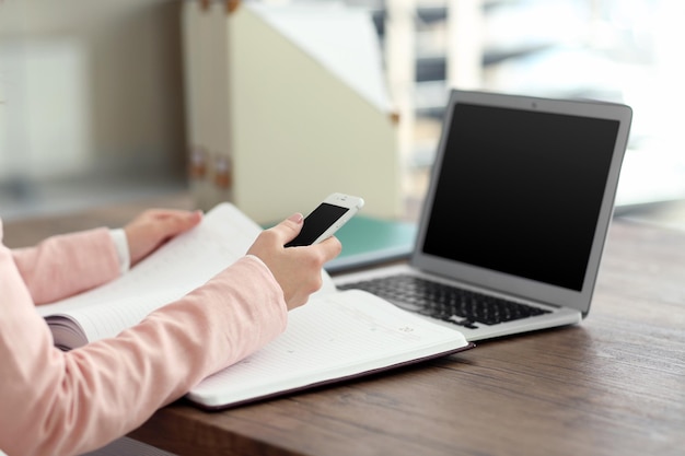 Mulher trabalhando com notebook e usando dispositivos na mesa no escritório