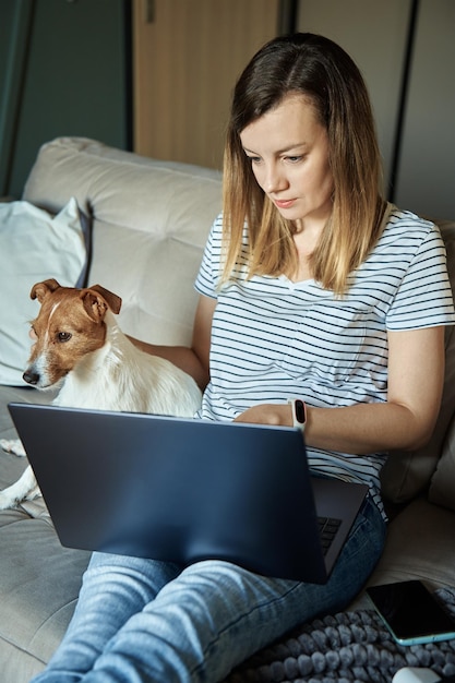 Mulher trabalhando em casa com cachorro de estimação usando laptop