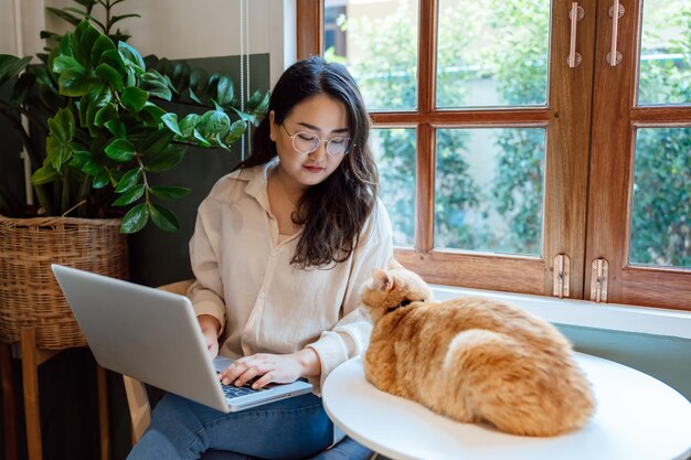 Mulher trabalhando em casa com gato dormindo no laptop assistente de teclado gato trabalhando no laptop