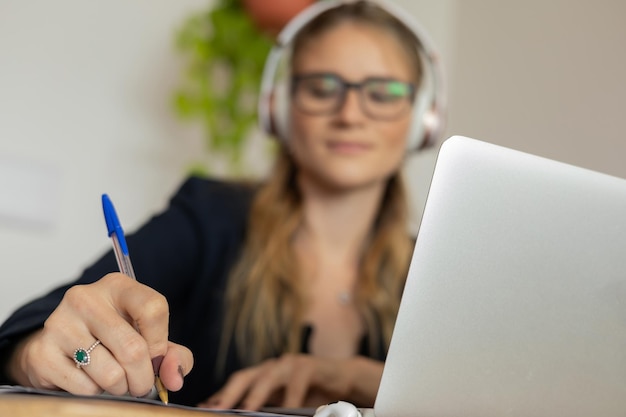 Foto mulher trabalhando em casa com laptop e papéis na mesa e fones de ouvido escritório em casa caderno cinza