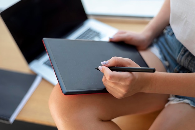 Mulher trabalhando em casa com tablet e laptop durante a pandemia