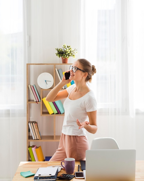 Mulher trabalhando em casa e falando no telefone