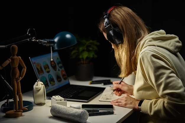 Mulher trabalhando em casa no local de trabalho à noite usando laptop