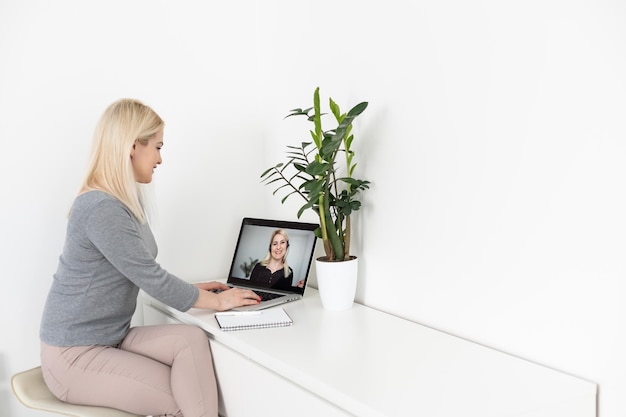 Mulher trabalhando em casa tendo videoconferência em grupo no Laptop.