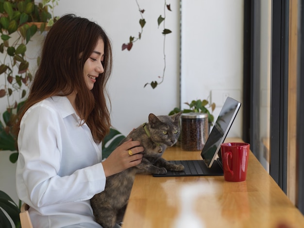 mulher trabalhando em tablet, com gato ao lado