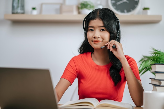 Mulher trabalhando, lendo um livro sobre a mesa e usando fones de ouvido