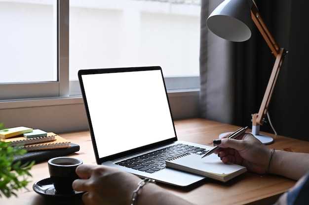 Mulher trabalhando online no laptop e fazendo anotações no notebook